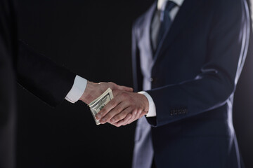 businessman hand giving money on black background