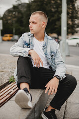 Urban Contemplation. Young Man in Denim Jacket Deep in Thought. City Musing. Brooding Young Guy in...