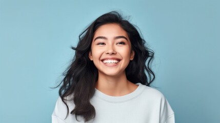 A carefree and jubilant young girl poses gracefully in front of a simple studio backdrop, her smile stealing the spotlight. - obrazy, fototapety, plakaty