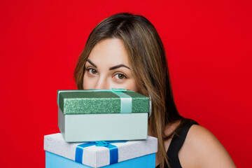 Large portrait of a young woman's face with boxes of Christmas gifts on a red background