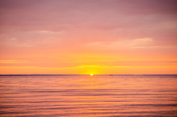 Beautiful bright picturesque dawn, sunrise on a river or sea in summer, through of clouds in the sky rays of red and orange color