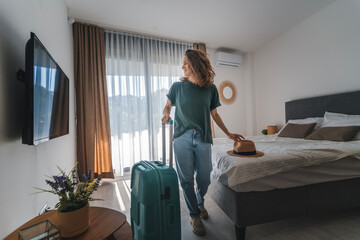 A young woman in a hat with a suitcase check in a hotel room. Booking and Accommodation travel...