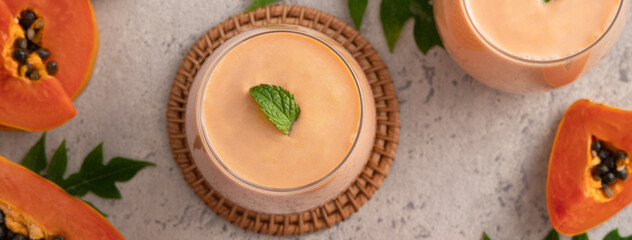 Delicious papaya milk smoothie in glass cup on gray table background