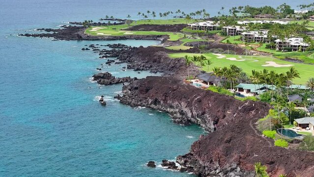 Aerial Kona Hawaii golf course luxury tropical resort coast. Big Island. Luxury exclusive homes on coast with golf course. Volcanic lava flow environment. Economy is tourism.