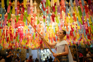 Beautiful Asian women holding a traditional paper lantern during Yi peng lantern festival at Wat Phra That Hariphunchai, Lamphun province, Thailand.