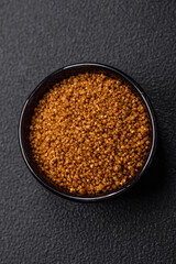 Crystals of brown Svan salt with spices in a black bowl