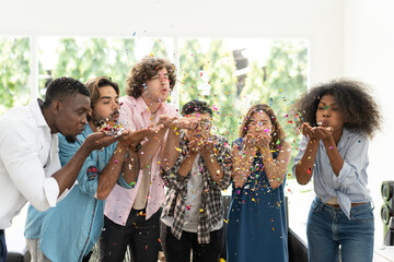 Group of multiethnic friends having fun at party playing fun blowing colorful paper - 659917081