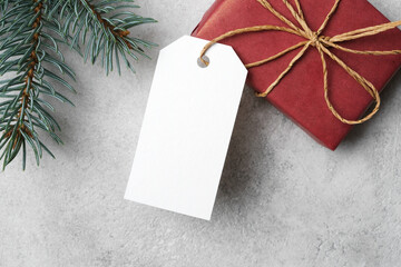 White blank paper tag or label with christmas gift box and fir tree branch, top view, copy space