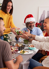 Vertical photo of family having lunch in Christmas day, sitting in the table all together, sharing food and enjoying each other company.