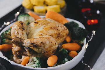 Homemade oven roasted chicken with vegetables on holiday table. Family festive dinner with autumn vegetables and poultry.