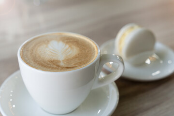 A cup of aromatic cappuccino and macaron on a table at the cafe. Selective focus.