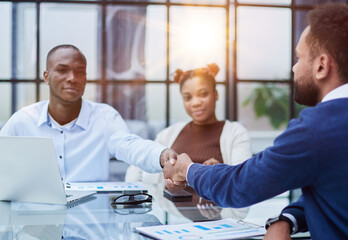 Obraz premium Overjoyed multiethnic businessmen shake hands greeting getting acquainted in office