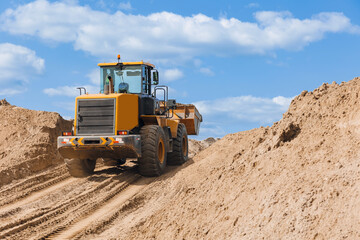 Concept heavy machinery of construction industry. Open pit mine quarry, yellow excavator transporting sand sunny day