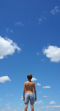 Low angle vertical shot. Child looking at blue-sky. Freedom concept.