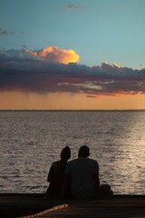 Coppia seduta sul pontile osserva il tramonto