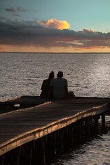 Coppia seduta sul pontile osserva il tramonto