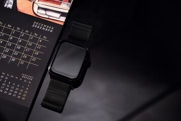 Smart watch and calendar on a black background. The layout of the holiday this year. Stock photo of the calendar