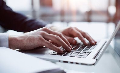 Closeup image of a man working and typing on laptop computer keyboard