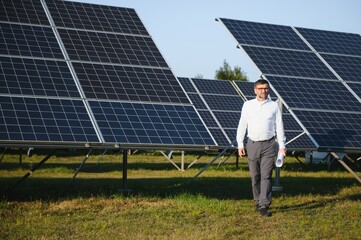 Senior male engineer inspects solar panels on farm. Clean energy.