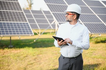 Senior male engineer inspects solar panels on farm. Clean energy.