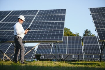 Engineer man in helmet in the field of solar panels