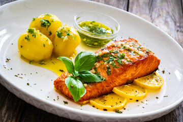 Seared salmon steak with boiled potatoes and lemon served on wooden table

