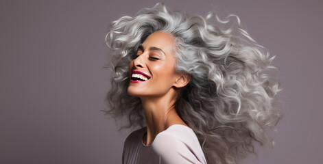 Fototapeta premium Black adult woman with smooth healthy skin. Beautiful aging mature woman with long gray hair and happy shy smiling. Beauty and cosmetics skincare advertising concept.