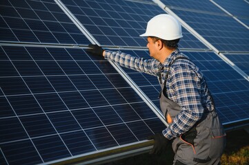 An Indian worker in uniform and with tools works on a solar panel farm