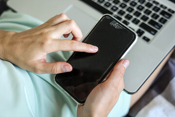 Unrecognisable woman is using, texting, messaging smartphone with a broken touch screen, glass with...