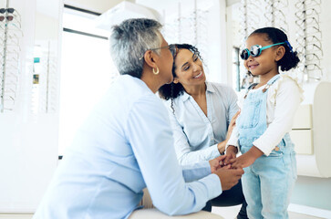 Fototapeta premium Optometrist, mother and child holding hands shopping for spectacles in trial frame at store. Mature ophthalmologist, mom and happy kid in test for glasses, vision and consulting for health or support