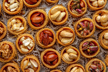 Bird's nest baklava with almonds, cashews, hazelnuts and pistachio. Turkish desert baklava with peanut for holiday or ramadan. Traditional Middle Eastern Flavors. Selective focus, pattern. - obrazy, fototapety, plakaty