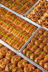 Different types of freshly baked baklava in baking trays. Turkish desert with peanut, pistachio for holiday or ramadan. Traditional Middle Eastern Flavors. Selective focus, pattern.