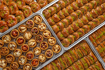 Different types of freshly baked baklava in baking trays. Turkish desert with peanut, pistachio for holiday or ramadan. Traditional Middle Eastern Flavors. Selective focus, pattern.