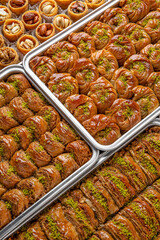 Different types of freshly baked baklava in baking trays. Turkish desert with peanut, pistachio for holiday or ramadan. Traditional Middle Eastern Flavors. Selective focus, pattern.