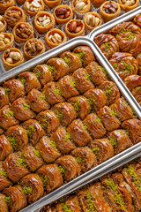 Different types of freshly baked baklava in baking trays. Turkish desert with peanut, pistachio for holiday or ramadan. Traditional Middle Eastern Flavors. Selective focus, pattern.