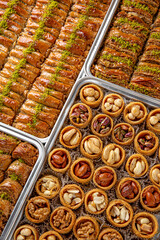 Different types of freshly baked baklava in baking trays. Turkish desert with peanut, pistachio for holiday or ramadan. Traditional Middle Eastern Flavors. Selective focus, pattern.