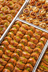 Different types of freshly baked baklava in baking trays. Turkish desert with peanut, pistachio for holiday or ramadan. Traditional Middle Eastern Flavors. Selective focus, pattern.