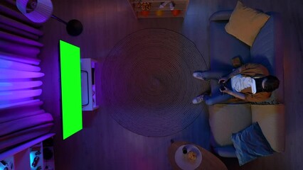 Top view man in VR glasses playing game on TV with Chroma key green screen, girl comes in and arguing with him, advertising area workspace mockup.