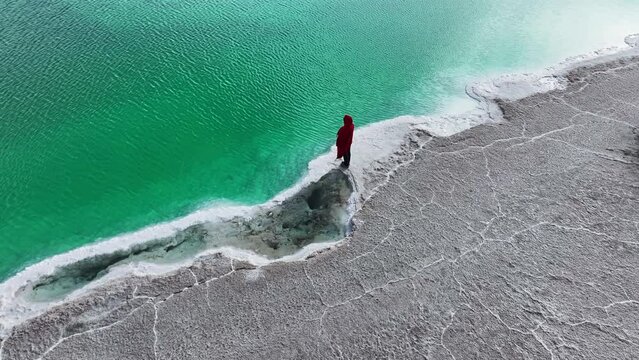 A woman in red dress standing at the Great Chaidan Emerald Lake in Qinghai province, China.