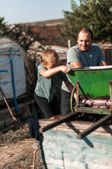 a little boy is busy processing grapes. happy father watching the process