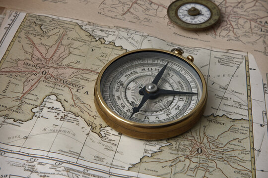 Travel, destination and history concept. Vintage compass placed on old and aged vintage map. Abstract background with copy space. Generative AI
