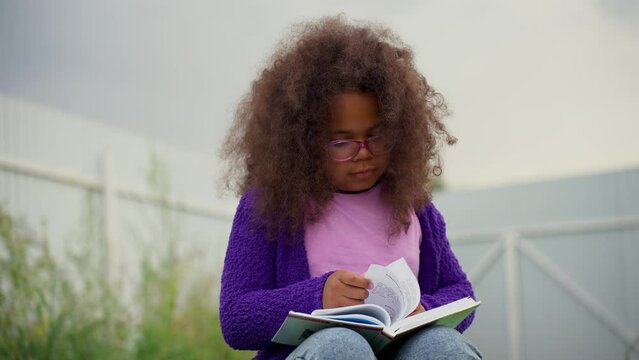 Little African American girl reading a book