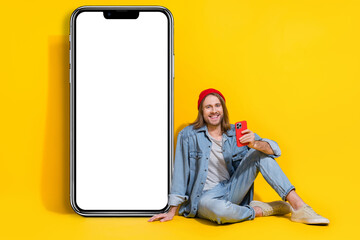 Full length photo of cool funny guy dressed jeans shirt texting twitter telegram empty space...