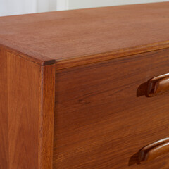 Vintage teak wood dresser. Mid-century modern gentleman's chest of drawers. Close-up view of the corner. 