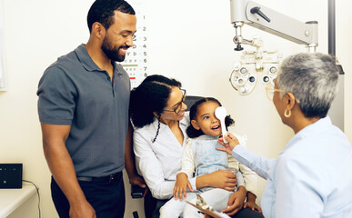 Family, optometry and eye exam with a woman doctor in a clinic to see a patient for vision assessment. Mother, father and daughter at the optometrist for an appointment to test eyesight for children © N F/peopleimages.com