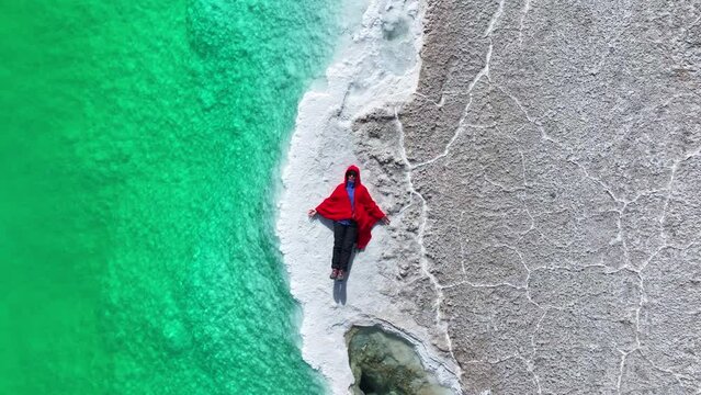A woman in red dress lying down at the Great Chaidan Emerald Lake in Qinghai province, China.