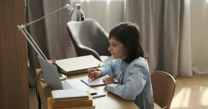 Caucasian schoolboy engages in an online lesson with focused attention. His dedication to learning through digital means illustrates the adaptability of modern education.