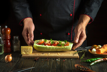 Professional chef prepares stuffed squash boats with minced meat and vegetables on the kitchen table. The concept of delicious national food zucchini for dinner