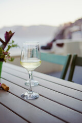 White wine served on a cold wineglass on a wooden table in Santorini, Greece