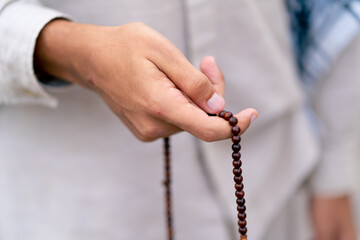 Male hands of an Islamic man holding rosary during prayer of conversion and worship of Allah